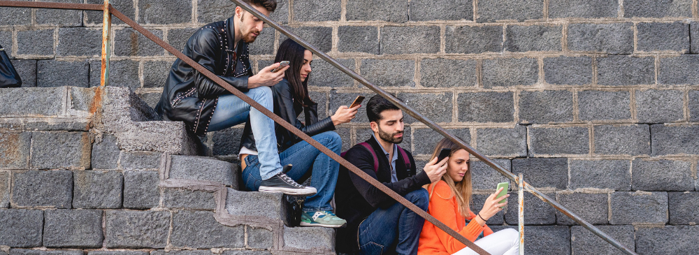 young adults holding a phone while sitting on stairs