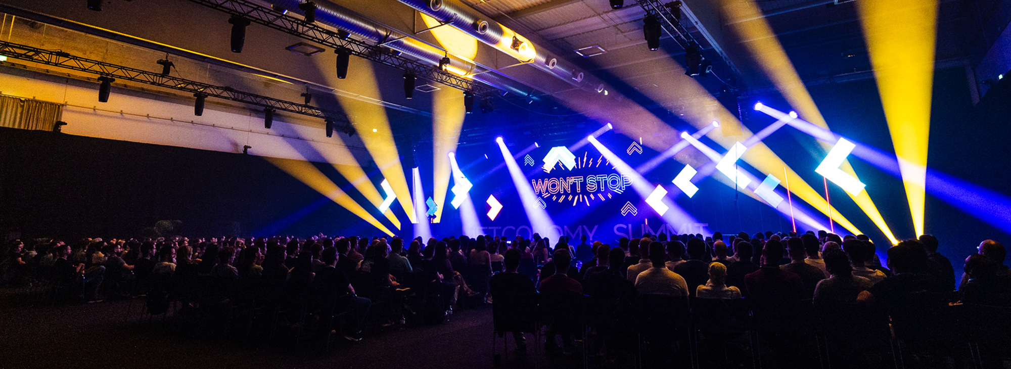 Image showing the opening of NETCONOMY Summit 2025 with dancing lights and a big crowd of people sitting in the audience.